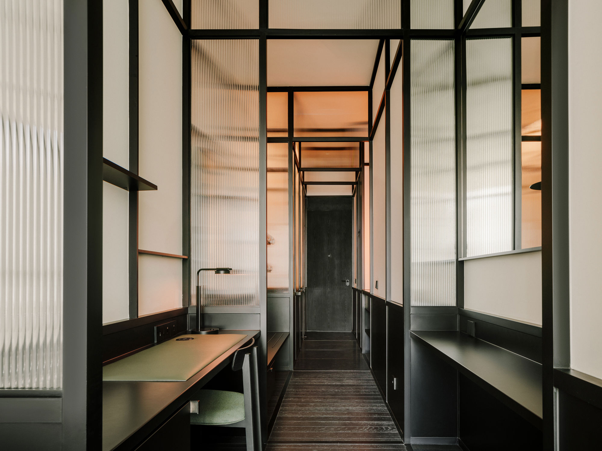 Sleek hotel bedroom with monochrome design and warm wood paneling in Tbilisi.